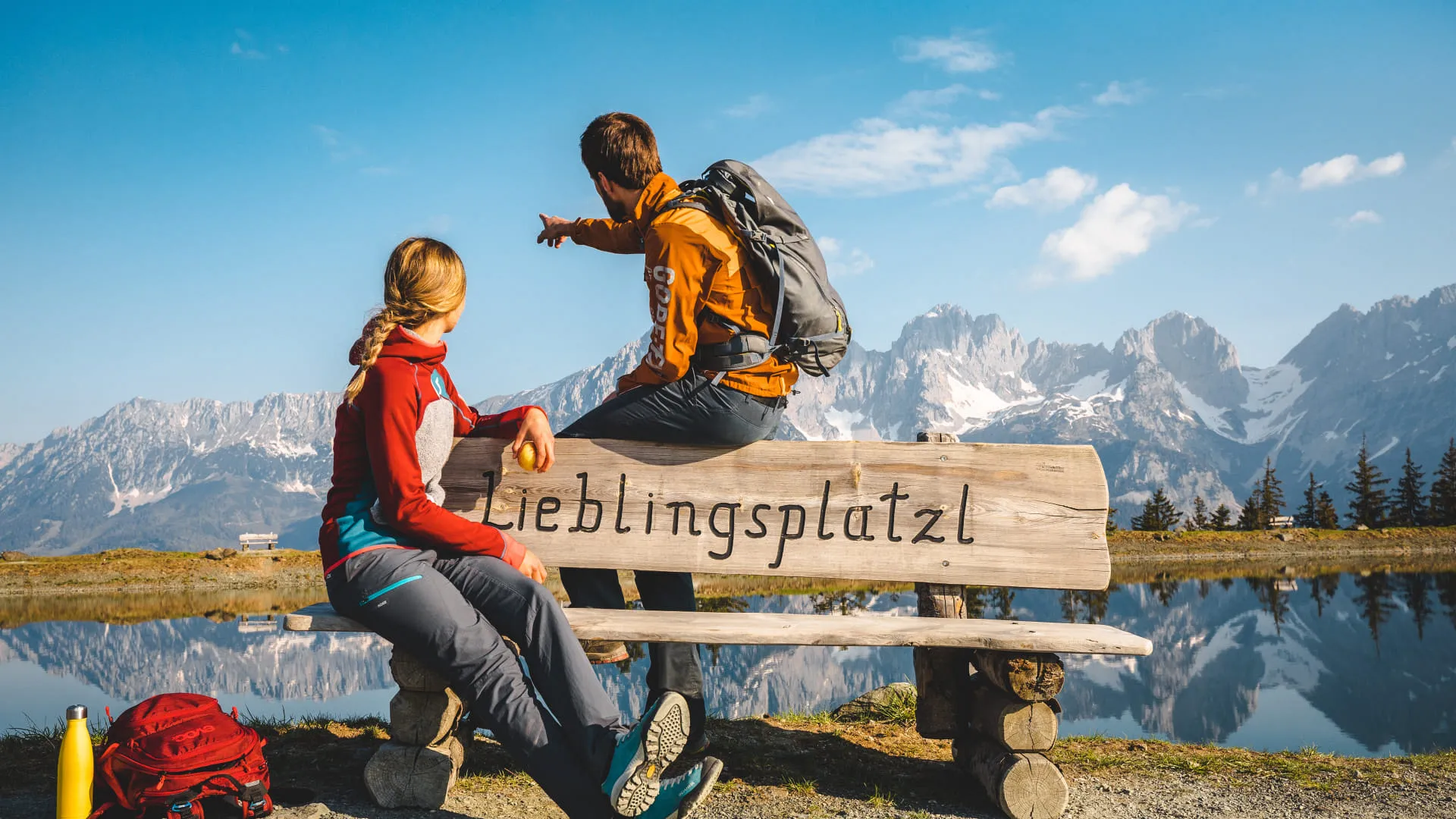 Zwei Wanderer sitzen auf einer Bank am Astbergsee.