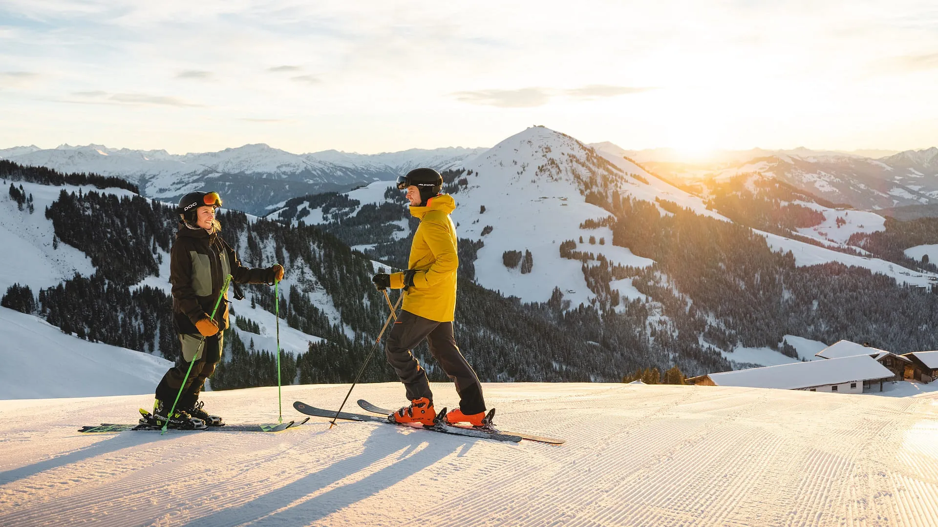 Zwei Skifahrer auf einer Piste im Sonnenuntergang