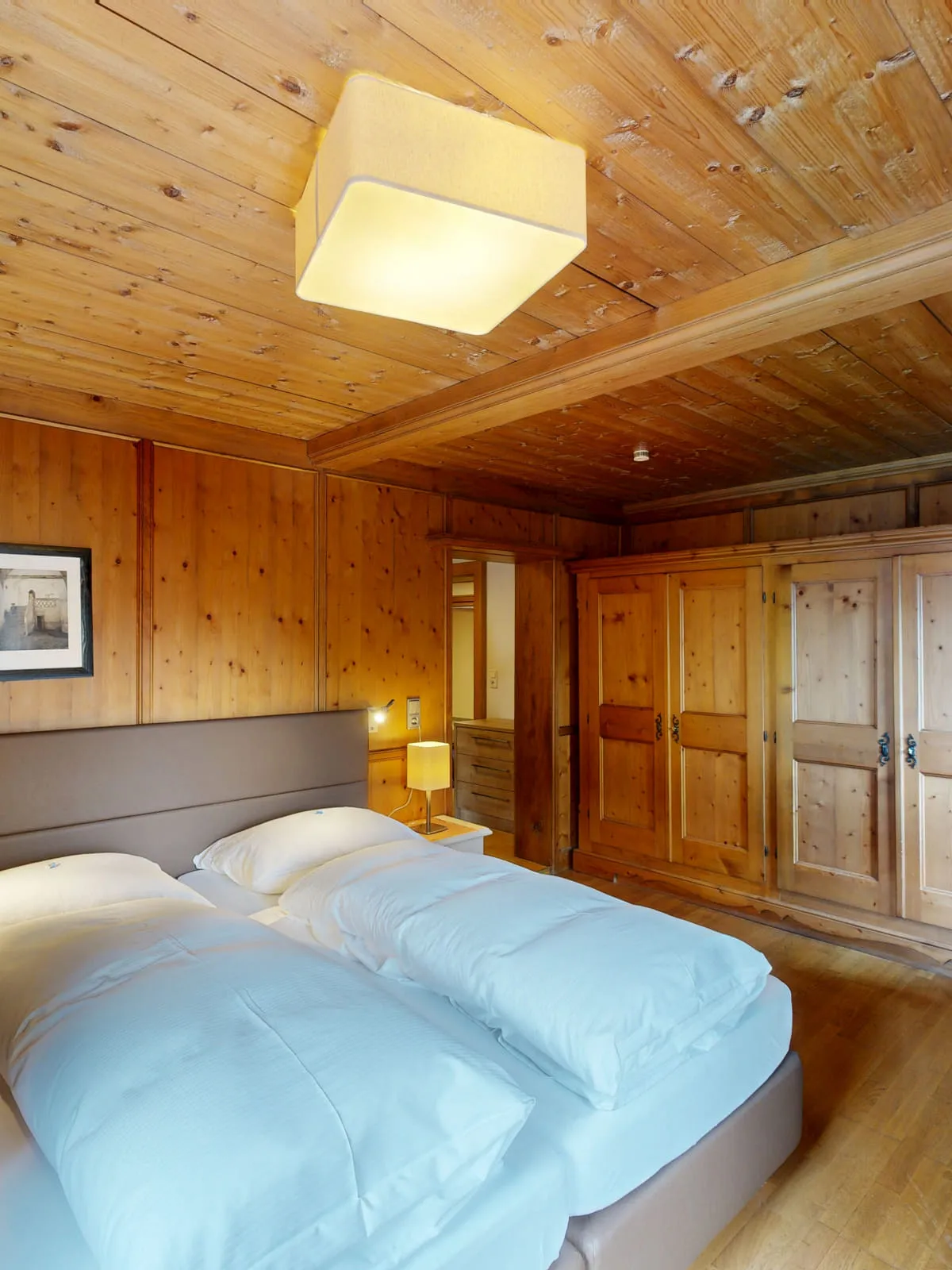 Holzvertäfeltes Schlafzimmer mit zwei Betten und Schrank