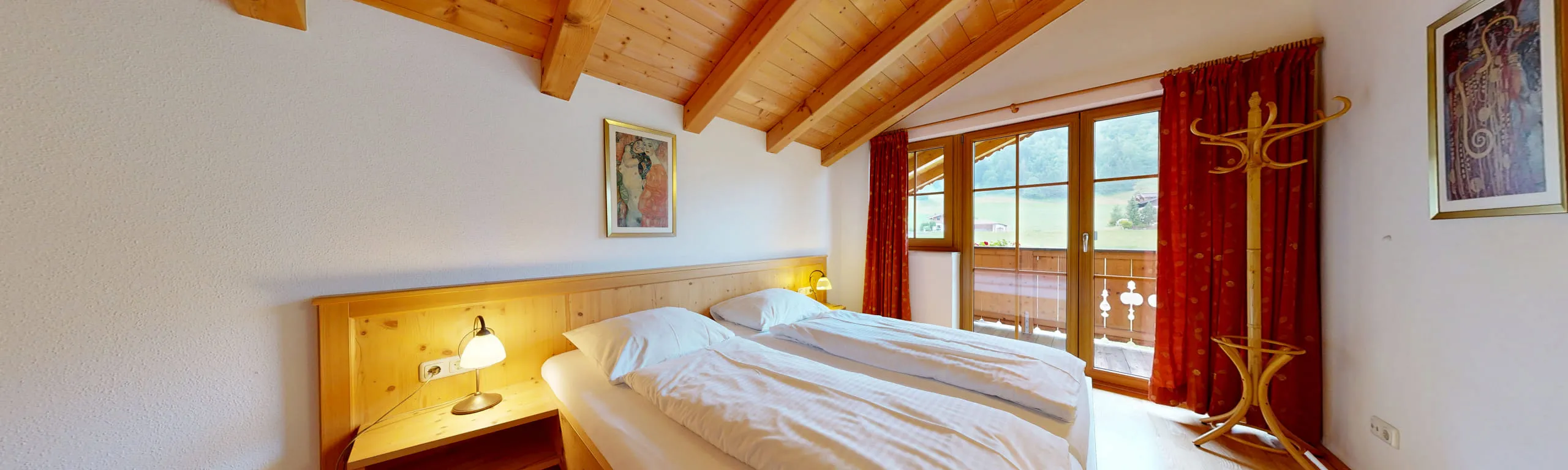 Helles Schlafzimmer mit Holzdecke und Fenster zum Balkon