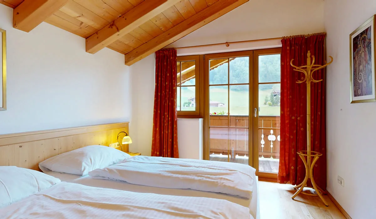 Gemütliches Schlafzimmer mit Balkon und Holzdecke.