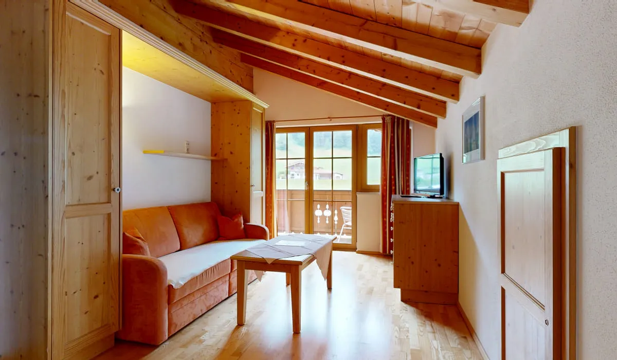 Gemütliches Zimmer mit Holzelementen und Balkon.