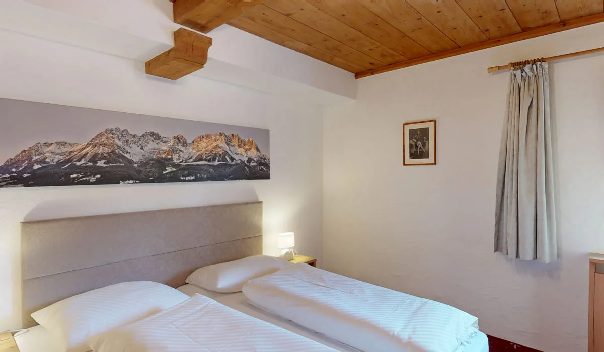 Schlafzimmer mit zwei Betten und Bergbild an der Wand