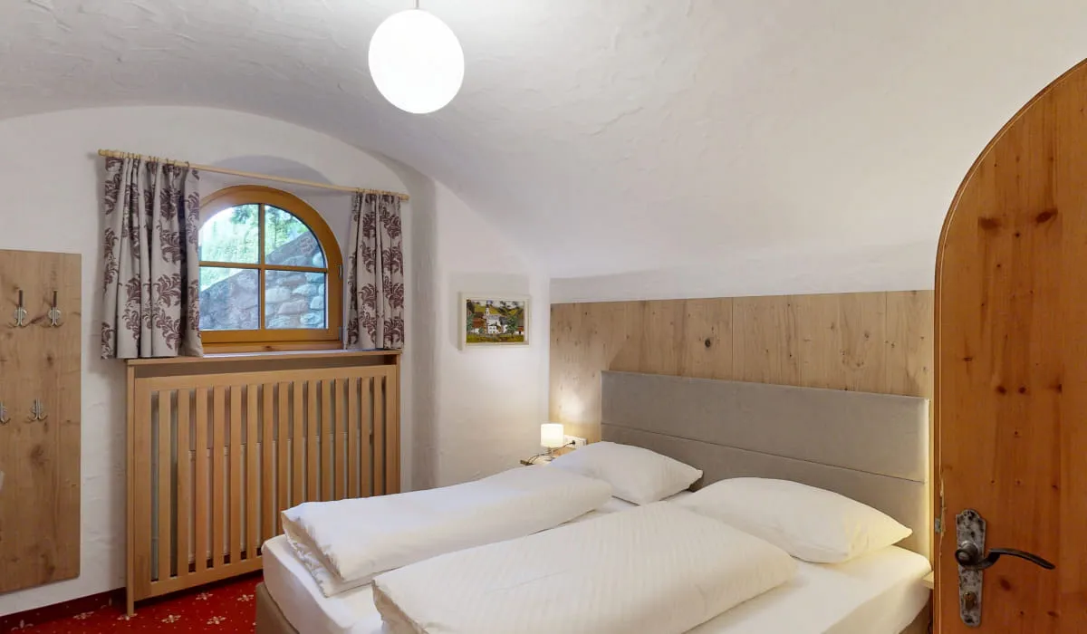 Helles Schlafzimmer mit runder Fenster und Holzelementen