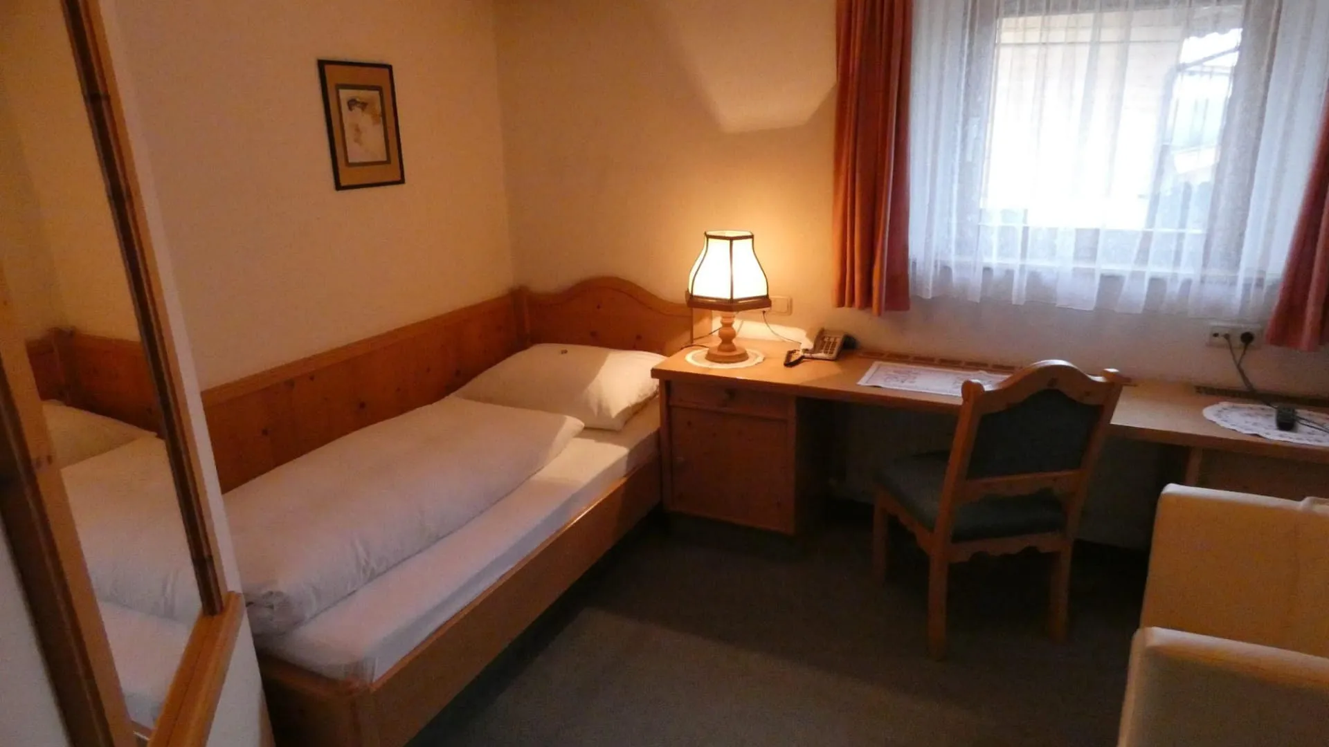 Gemütliches Einbettzimmer mit Bett und Schreibtisch.